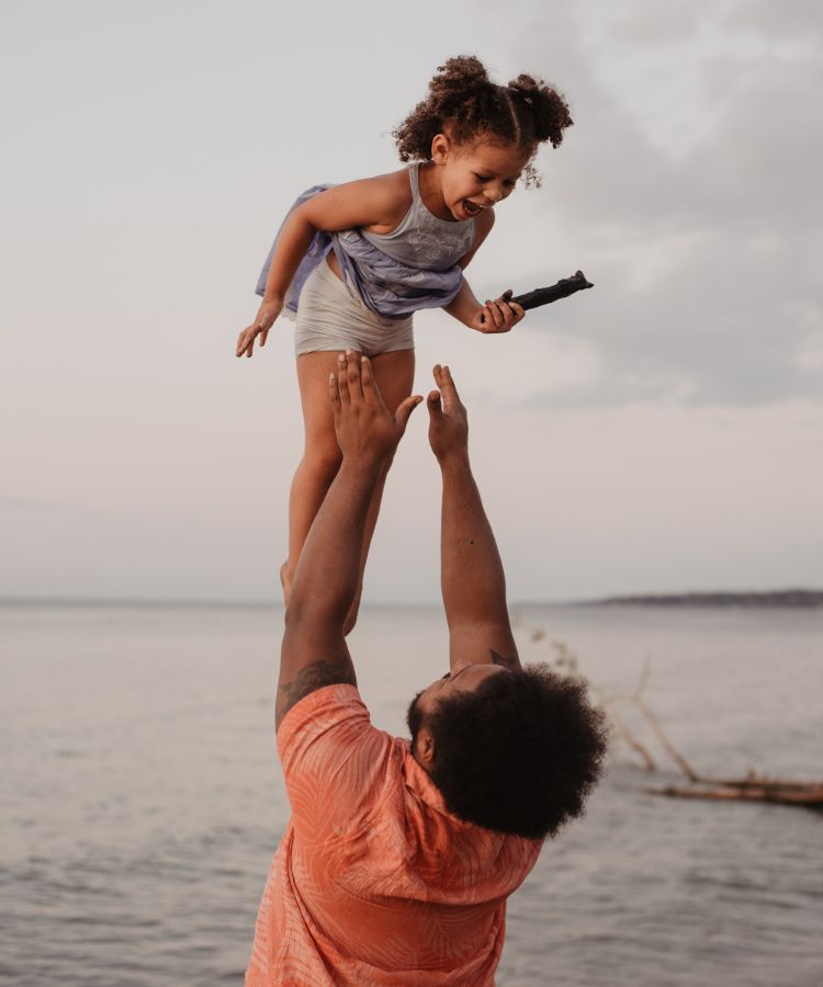 a father throwing up his laughing child into the air
