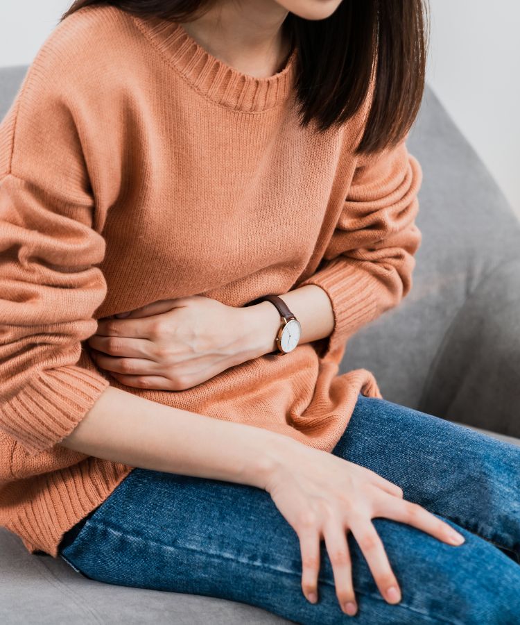 a young woman, holding her stomach, seemingly in pain or discomfort